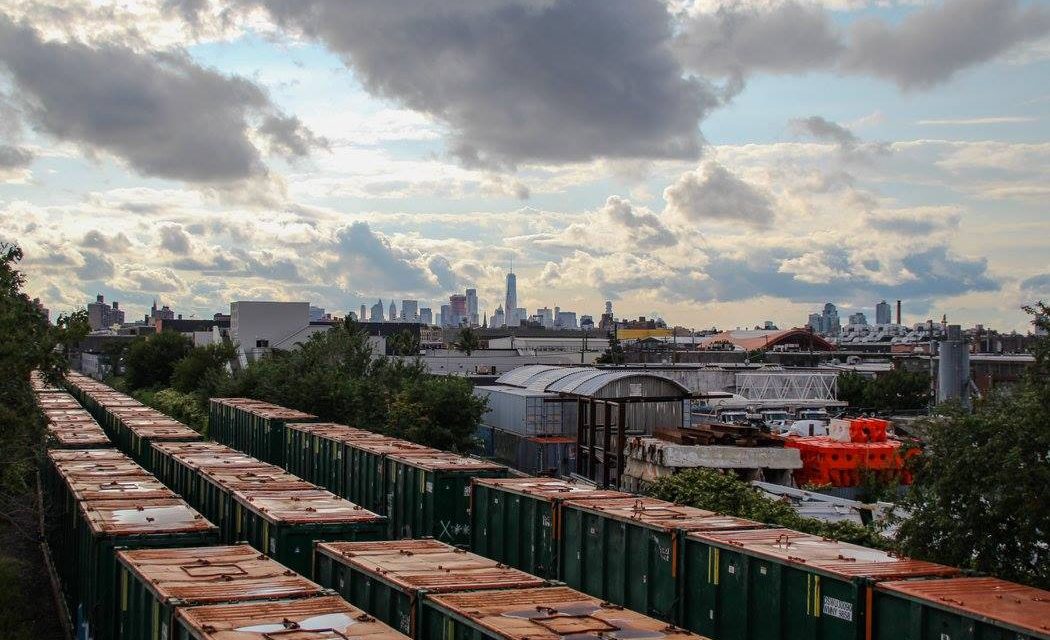 Вагоны с нью-йоркским мусором, скайлайн Манхэттена и небо, Бушвик.